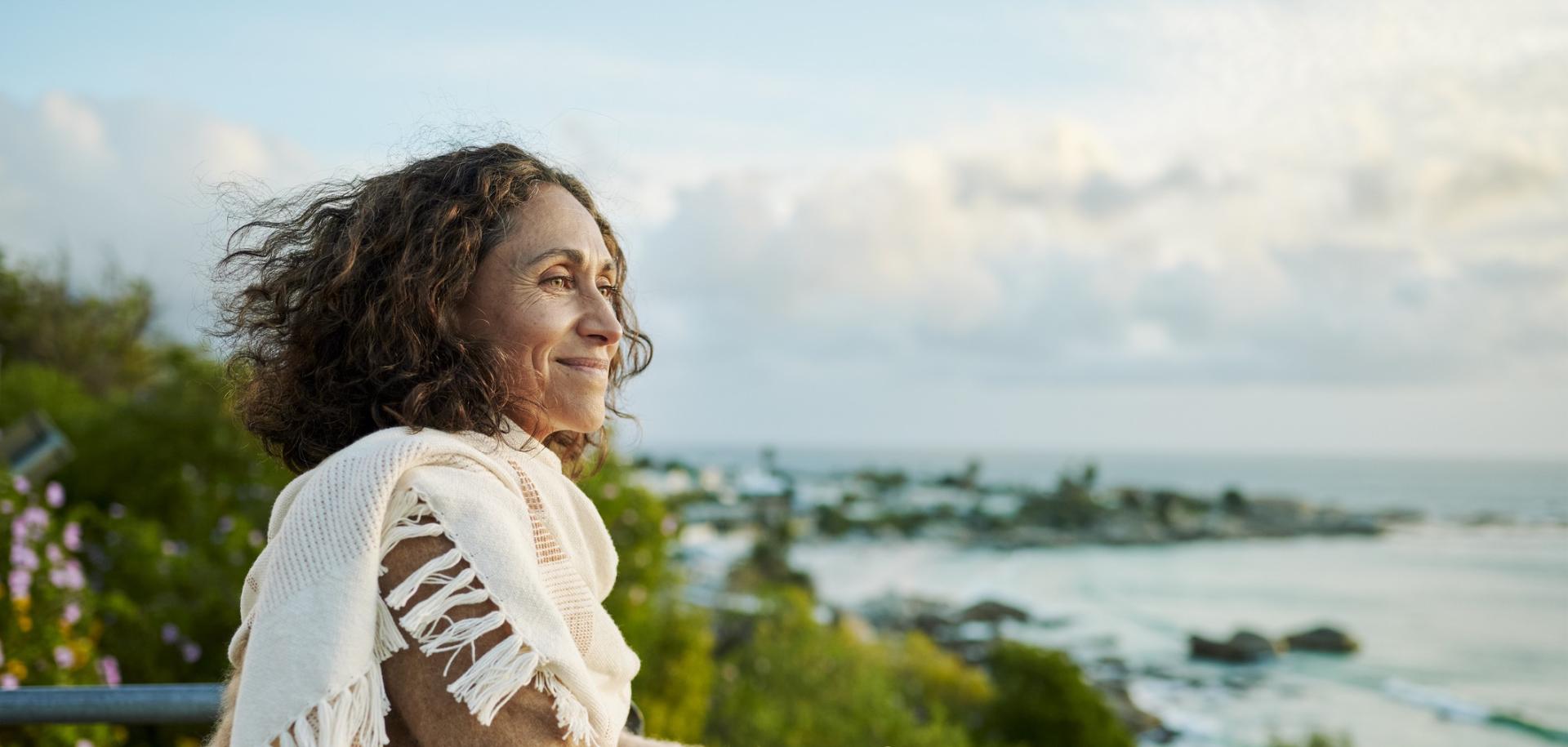 Woman smiling while looking over lookout spot to the ocean