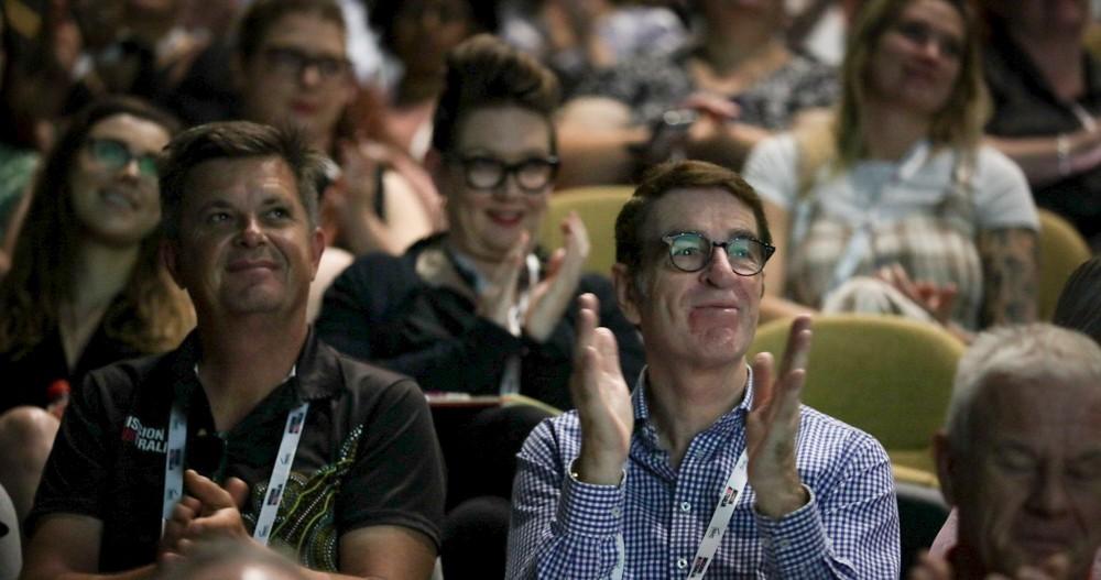 Person in conference audience smiling and clapping